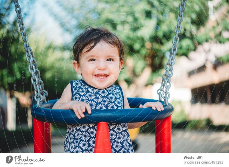 Porträt eines lachenden Mädchens, das auf einem Spielplatz in Schaukel sitzt Schaukeln weibliche Babys weibliches Baby weibliche Babies Portrait Porträts