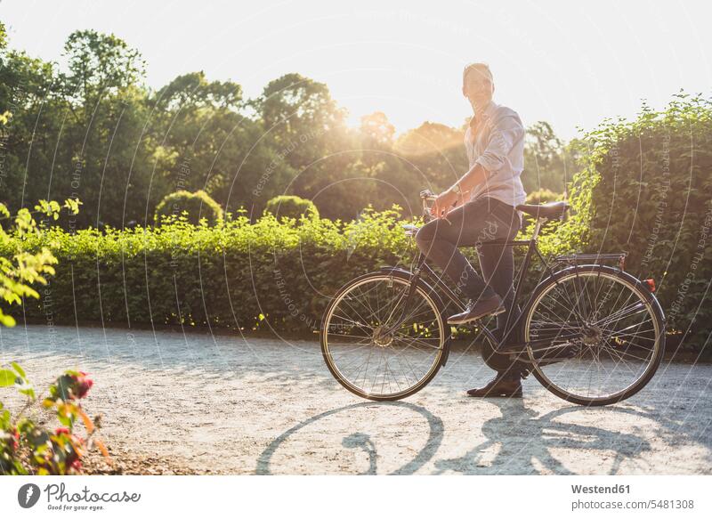 Mann mit Fahrrad in einem Park bei Sonnenaufgang Männer männlich Bikes Fahrräder Räder Rad Parkanlagen Parks Erwachsener erwachsen Mensch Menschen Leute People