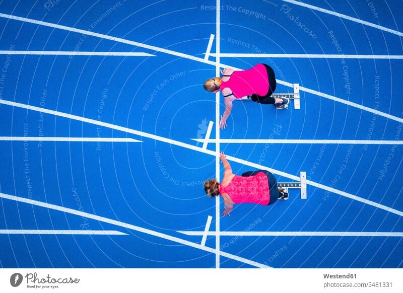 Draufsicht auf zwei Läuferinnen, die auf der Tartanbahn starten Vogelperspektive von oben Aufsicht Laeuferinnen Laufbahn Rennbahn Frau weiblich Frauen