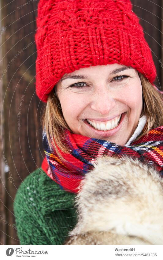 Porträt einer glücklichen Frau mit rotem Pudelhut im Winter winterlich Winterzeit Portrait Porträts Portraits weiblich Frauen Erwachsener erwachsen Mensch