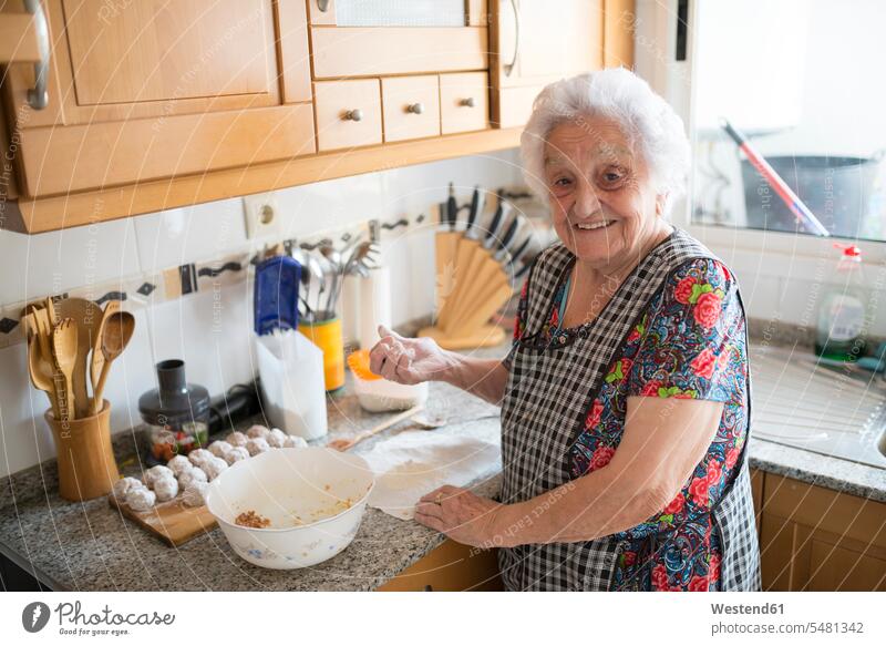 Porträt einer lächelnden älteren Frau, die in der Küche Fleischbällchen zubereitet Küchen Seniorin Seniorinnen alt Portrait Porträts Portraits Senioren weiblich