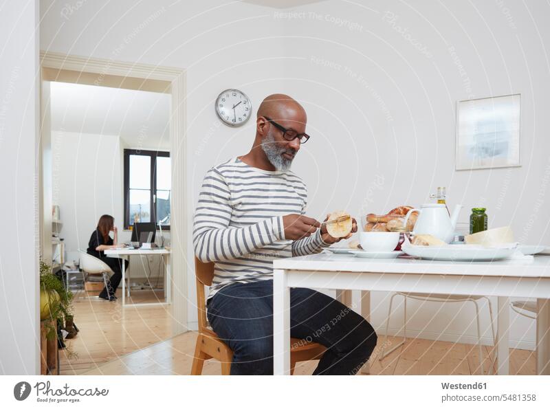 Mann frühstückt spät in seinem Heimbüro Afroamerikanisch Afro-Amerikanisch Afroamerikaner Afro-Amerikaner Glatze Glatzen kahl Blick nach unten Arbeitsbereich