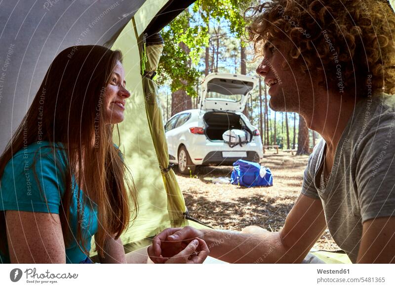 Lächelndes junges Paar in einem Zelt lächeln Pärchen Paare Partnerschaft Zelte Mensch Menschen Leute People Personen erholen erholend positiv Individualität