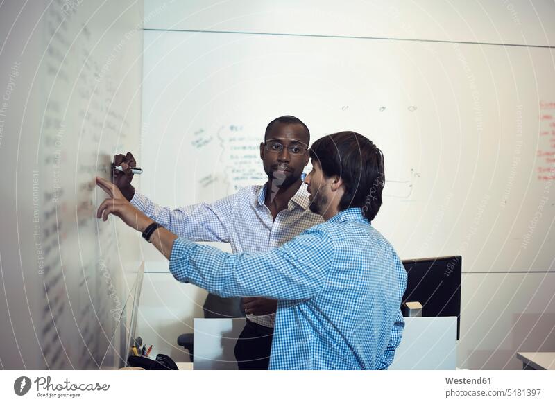 Geschäftsleute schreiben im Büro auf Whiteboard Präsentation Praesentationen Präsentationen besprechen diskutieren Besprechung Weißwandtafel zeigen