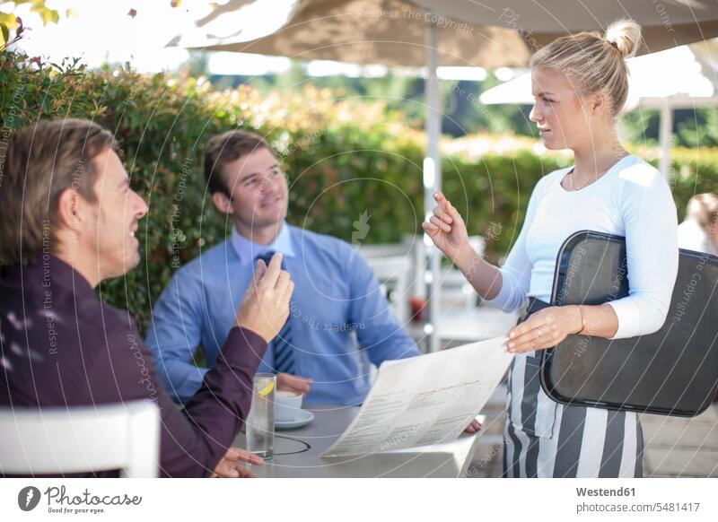 Kellnerin im Gespräch mit zwei Geschäftsleuten im Außenrestaurant Restaurantfachfrau Kellnerinnen Gartenrestaurant Ober Bedienung Bedienungspersonal Service