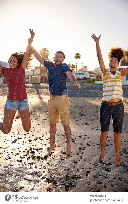 Glückliche Freunde springen am Strand in die Luft Beach Straende Strände Beaches Freundschaft Kameradschaft hüpfen Freude freuen Begeisterung Enthusiasmus