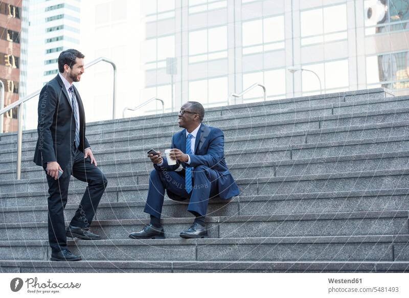 Zwei Geschäftsleute unterhalten sich auf einer Treppe Geschäftsmann Businessmann Businessmänner Geschäftsmänner Treppenaufgang Kollegen Arbeitskollegen sprechen
