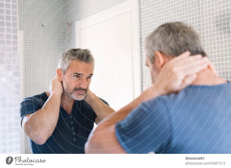 Reifer Mann schaut in den Badezimmerspiegel Männer männlich Spiegel schauen schauend anschauen betrachten Zimmer Raum Räume Erwachsener erwachsen Mensch