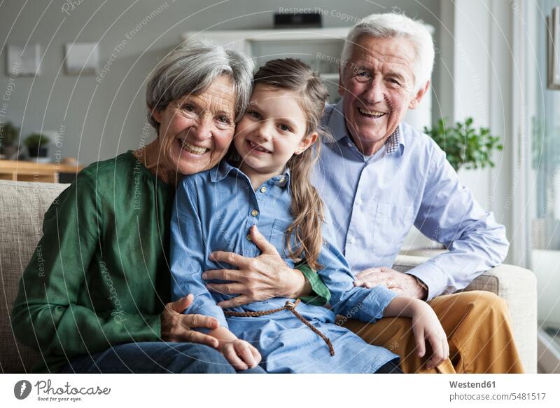 Familienportrait der Großeltern und ihrer Enkelin zu Hause Deutschland Mädchen weiblich Wohnen Kindheit offenes Lächeln lachen offenes Laecheln Kopf an Kopf