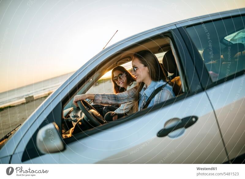 Zwei junge Frauen reisen in einem Auto Wagen PKWs Automobil Autos Freundinnen Kraftfahrzeug Verkehrsmittel KFZ Freunde Freundschaft Kameradschaft autofahren
