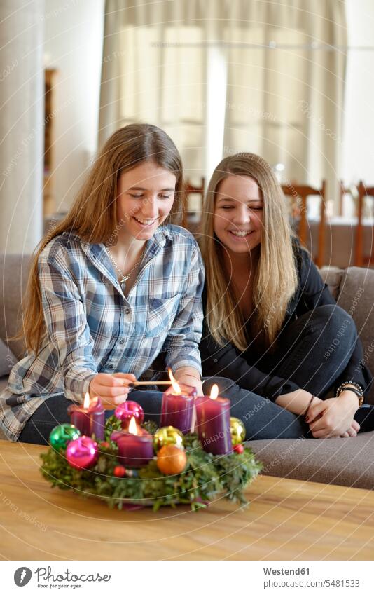 Junge Frau zündet Kerze am Adventskranz an, während ihr Freund zuschaut Oberbayern anzünden Gemeinsamkeit zusammen gemeinsam Zuversicht Zuversichtlich