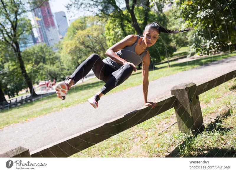Frau springt im Park über den Zaun weiblich Frauen trainieren springen hüpfen Erwachsener erwachsen Mensch Menschen Leute People Personen Sprung Spruenge