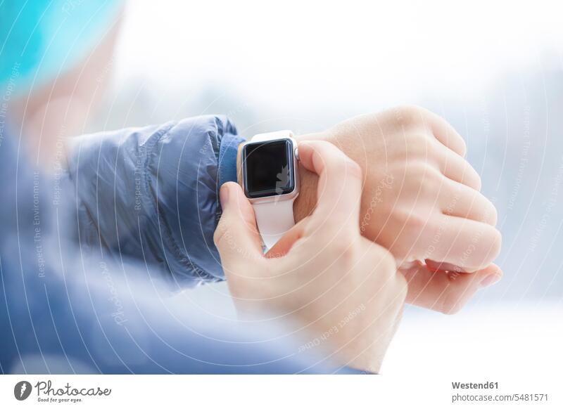 Sportlicher Mann überprüft seine Smartwatch im Winter, Nahaufnahme Hand Hände überprüfen testen checken Mensch Menschen Leute People Personen benutzen benützen