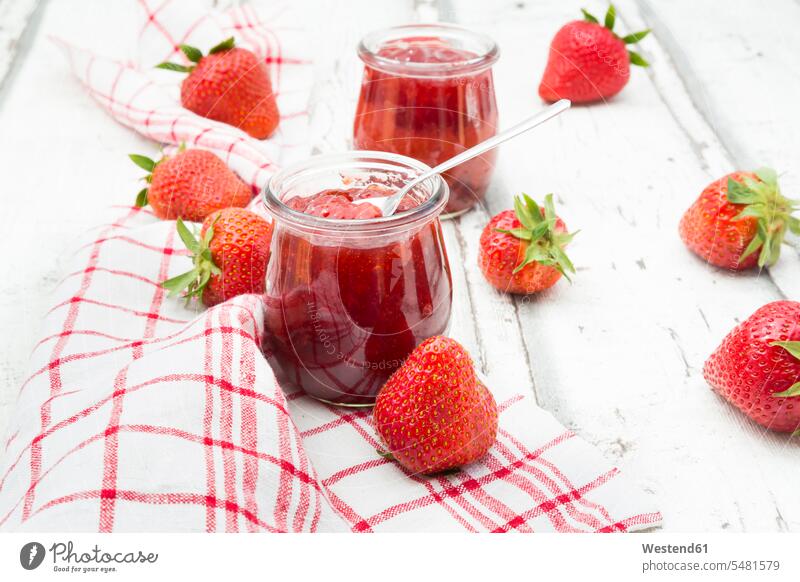 Glas mit hausgemachter Erdbeermarmelade, Küchentuch und Erdbeeren auf weißem Holz Gläser Frucht Früchte Fruechte selbstgemacht selbstgemachte Marmeladenglas