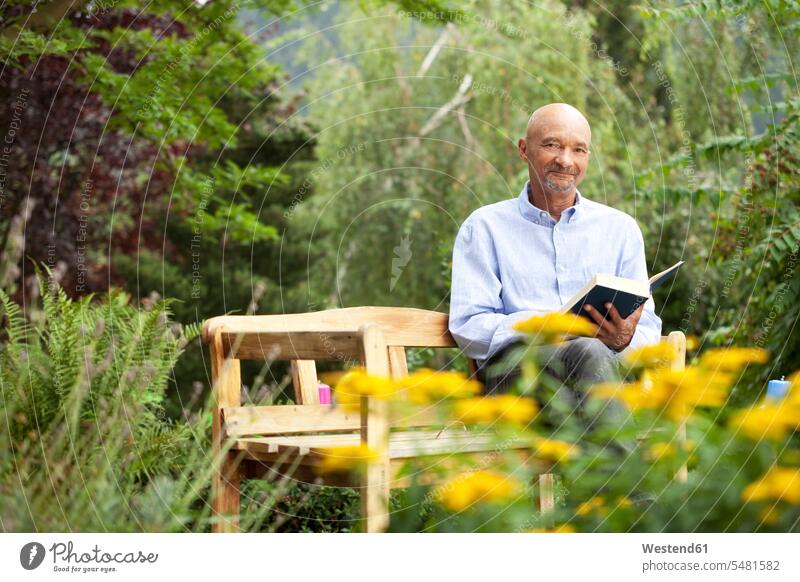 Älterer Mann sitzt auf Gartenbank und liest Buch sitzen sitzend Senior ältere Männer älterer Mann Senioren Gärten Gaerten lesen Lektüre Bücher Bank Sitzbänke