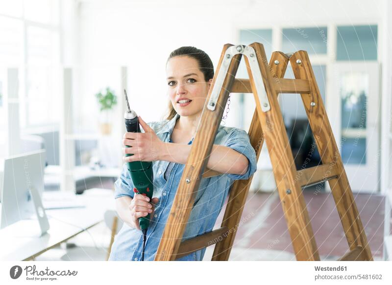 Porträt einer Frau an einer Leiter, die eine elektrische Bohrmaschine hält Umzug umziehen Leitern weiblich Frauen Schlagbohrer Bohrer Bohrmaschinen Portrait