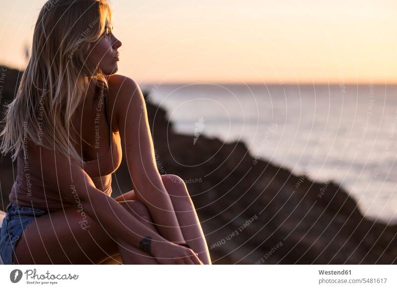 Spanien, Teneriffa, Porträt einer blonden Frau, die den Sonnenuntergang am Meer genießt Meere sitzen sitzend sitzt Sonnenuntergänge Portrait Porträts Portraits