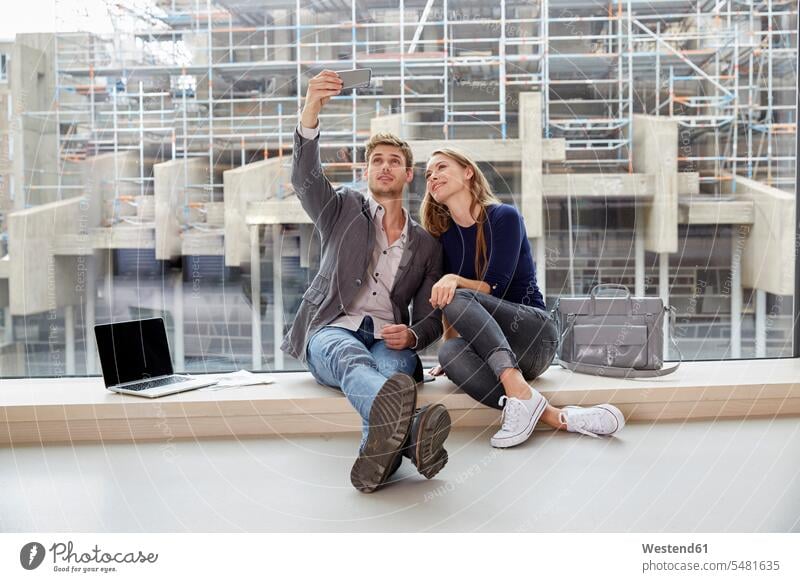 Junges Paar sitzt am Fenster und macht ein Selfie lächeln Pärchen Paare Partnerschaft Selfies Handy Mobiltelefon Handies Handys Mobiltelefone Mensch Menschen