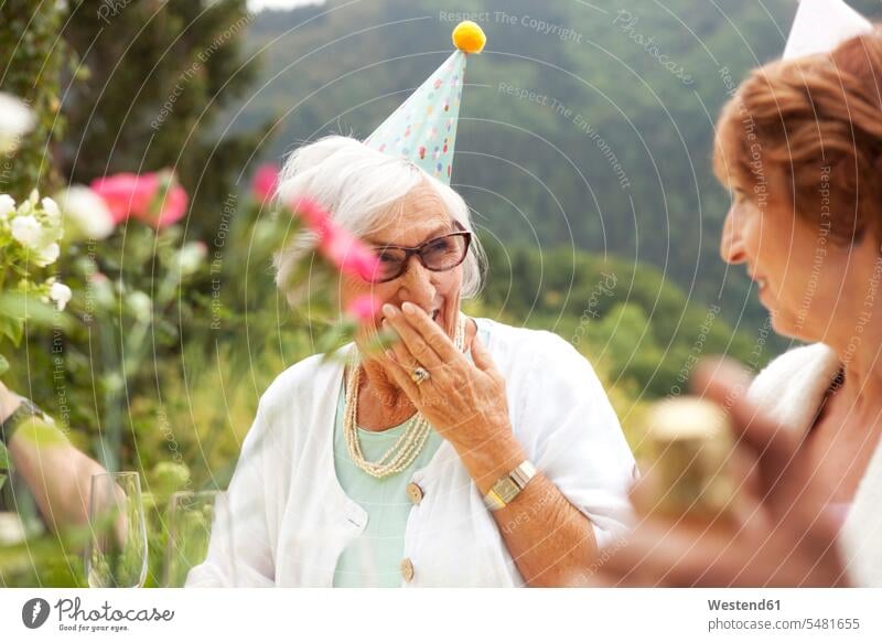 Seniorinnen lachen bei der Feier, tragen Partyhüte trinken beschwipst Sekt fröhlich Fröhlichkeit Frohsinn Heiterkeit Senioren alte ältere feiern ausgelassen