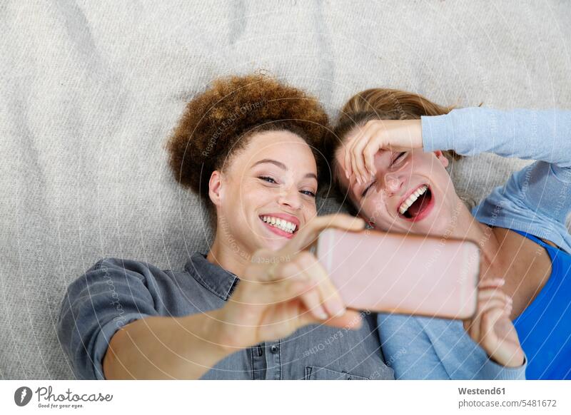 Zwei glückliche junge Frauen machen ein Selfie auf einer Decke Freundinnen lächeln Selfies weiblich Freunde Freundschaft Kameradschaft Erwachsener erwachsen