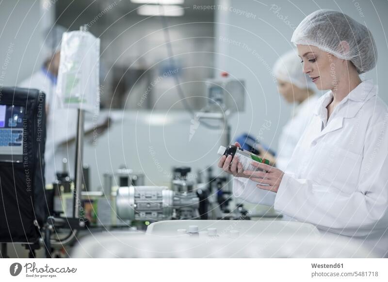Frau in pharmazeutischer Fabrik schaut auf Kolben arbeiten Arbeit Fabriken Fläschchen weiblich Frauen Erwachsener erwachsen Mensch Menschen Leute People