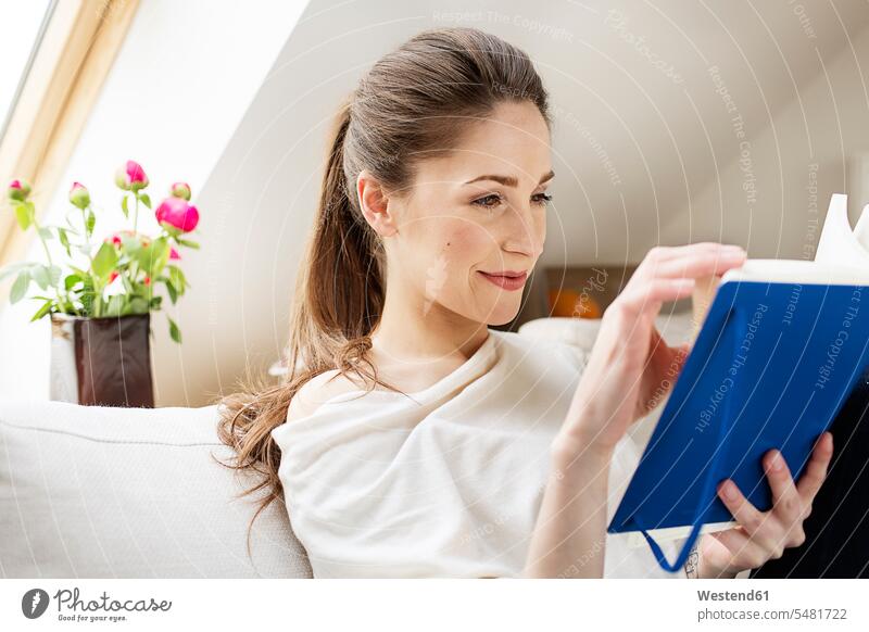 Lächelnde junge Frau liest Buch weiblich Frauen lesen Lektüre Bücher Erwachsener erwachsen Mensch Menschen Leute People Personen lächeln Europäer Kaukasier