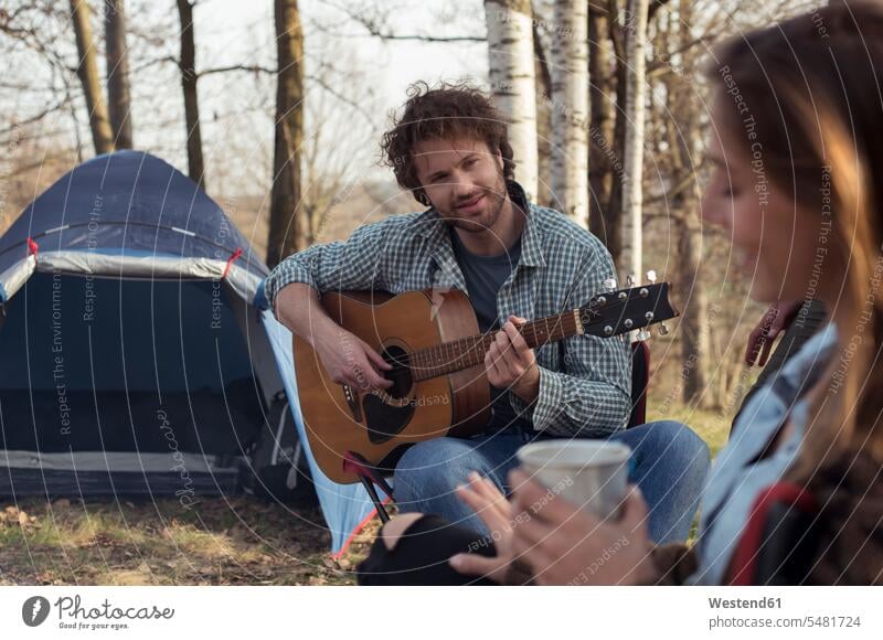 Ehepaar zeltet im Wald mit Gitarre spielendem Mann Camping Campen zelten lächeln Forst Wälder Paar Pärchen Paare Partnerschaft Gitarren Mensch Menschen Leute
