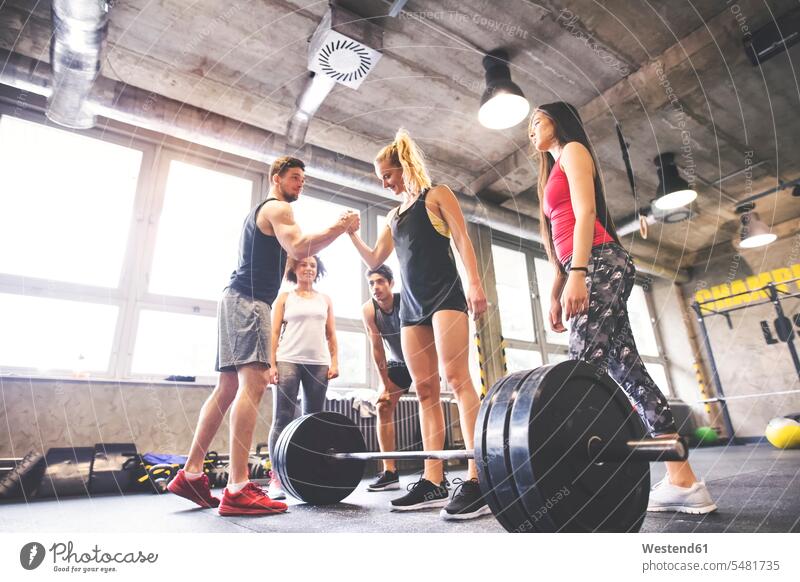 Gruppe junger fitter Menschen, die Frauen zum Gewichtheben im Fitnessstudio motivieren trainieren Kraftsport Sport Gesundheit gesund Fitnesstraining