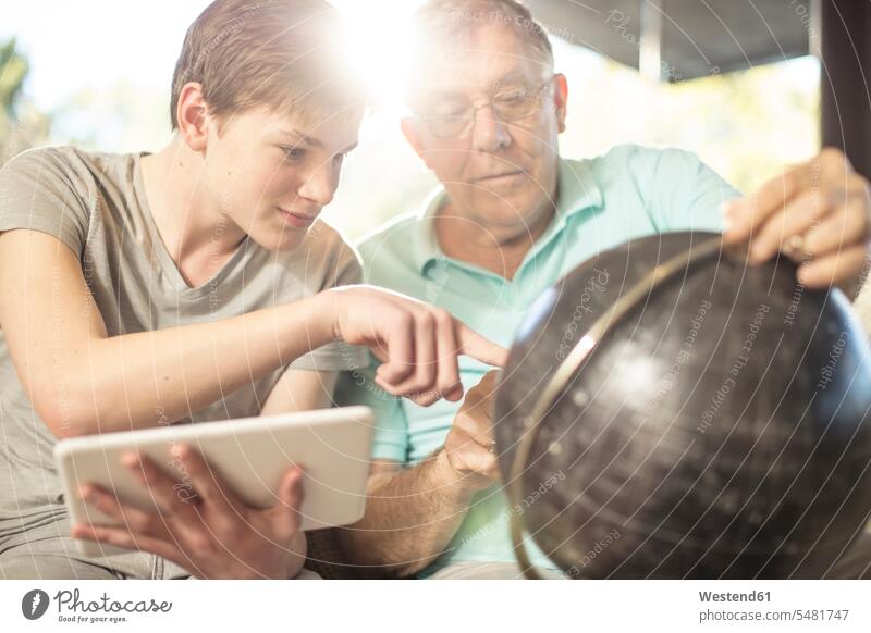 Gandvater und Enkel schauen gemeinsam auf den Erdglobus Gemeinsam Zusammen Miteinander Zuhause zu Hause daheim Globus Weltkugel Erdkugel Globen Enkelsöhne