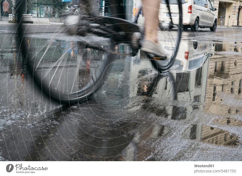 Fahrradfahren in der Stadt an einem regnerischen Tag, Teilansicht Bikes Fahrräder Räder Rad Städtische Straße Strassen Straßen Asphalt Unterer Ausschnitt