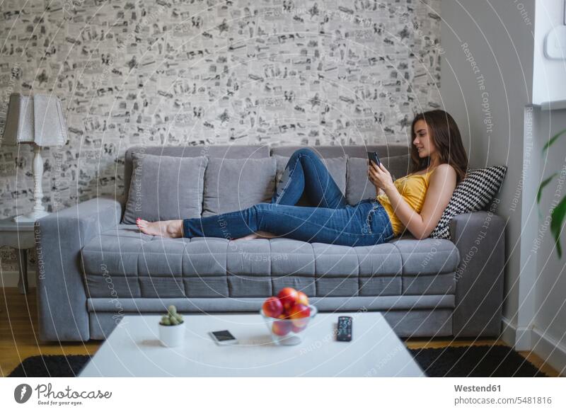 Frau auf der Couch im Wohnzimmer liest E-Book lesen Lektüre weiblich Frauen Erwachsener erwachsen Mensch Menschen Leute People Personen Sofa Couches Liege Sofas