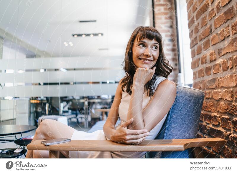 Geschäftsfrau, die im Büro auf der Couch sitzt und lächelt sitzen sitzend lächeln Office Büros Pause Pause machen Geschäftsfrauen Businesswomen Businessfrauen