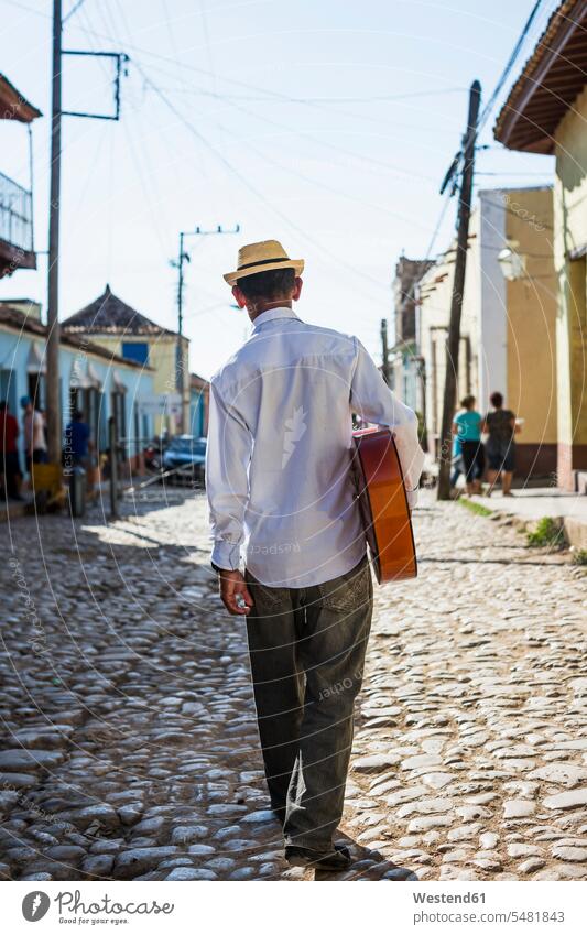 Kuba, Trinidad, Rückenansicht eines Mannes mit Gitarre, der auf der Straße geht Männer männlicher Erwachsener männliche Erwachsene Straßenmusiker erwachsen