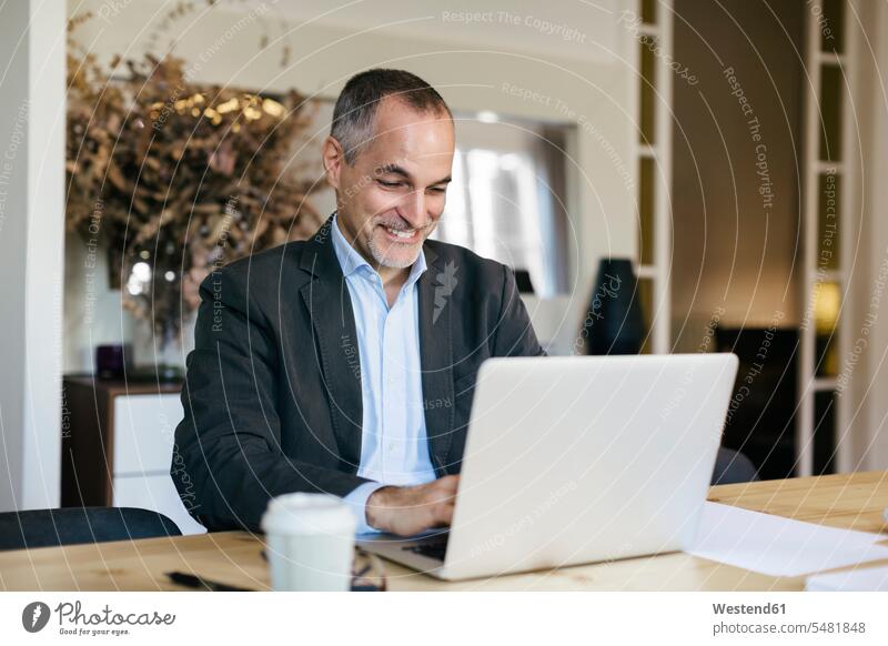 Erfolgreicher Geschäftsmann sitzt am Schreibtisch und arbeitet am Laptop Erfolge erfolgreich sitzen sitzend arbeiten Arbeit Notebook Laptops Notebooks