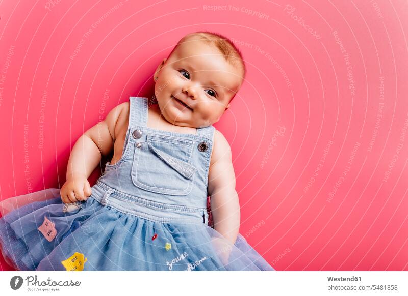 Porträt eines lächelnden Mädchens auf rosa Hintergrund Baby Babies Babys Säuglinge Kind Kinder liegen liegend liegt Portrait Porträts Portraits Babyportrait