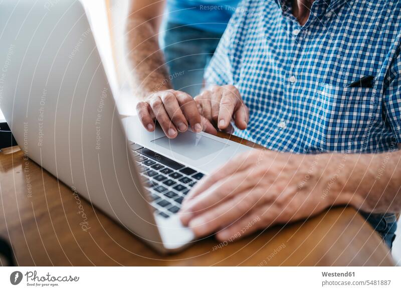 Erwachsener Enkel, der seinem Großvater den Umgang mit dem Laptop beibringt, Nahaufnahme Notebook Laptops Notebooks Hand Hände Senior ältere Männer älterer Mann