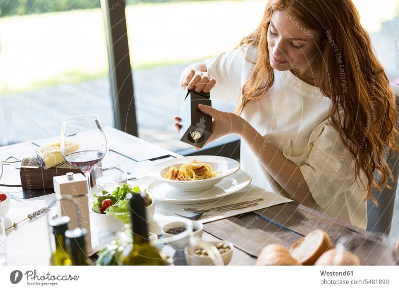 Frau würzt ihre Spaghetti Carbonara weiblich Frauen essen essend genießen geniessen Genuss Spagetti würzen Pfeffermühle Pfeffermuehle Erwachsener erwachsen