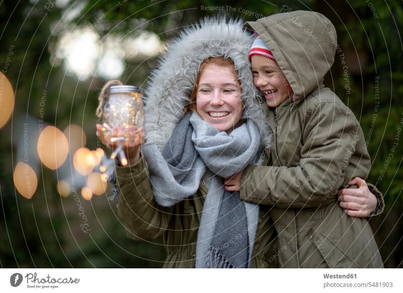 Glückliche Teenagerin und ihre kleine Schwester mit selbstgemachtem Geschenk im Freien schenken Geschenke Schwestern glücklich glücklich sein glücklichsein