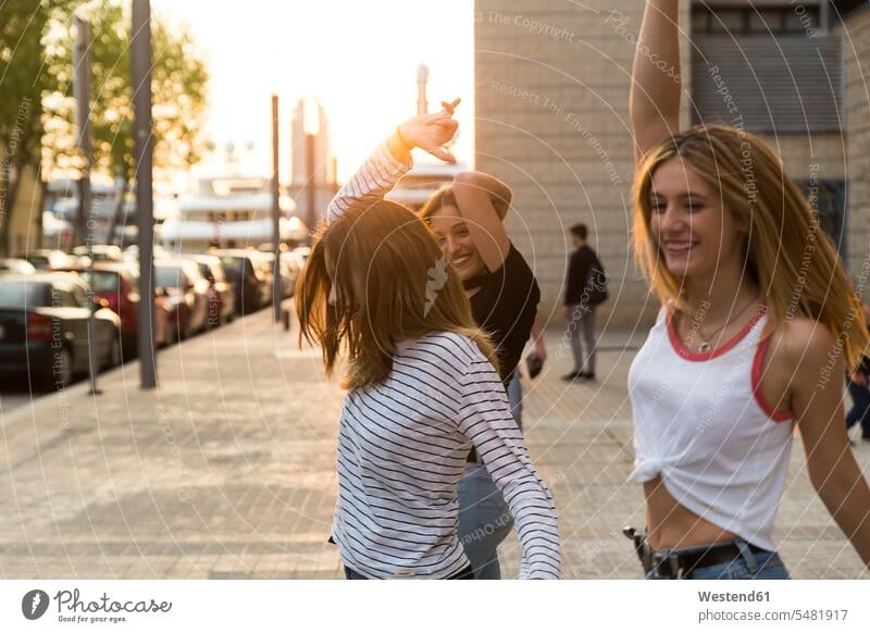 Drei Freunde tanzen auf dem Bürgersteig tanzend Freundinnen Freundschaft Kameradschaft lächeln Frau weiblich Frauen Erwachsener erwachsen Mensch Menschen Leute