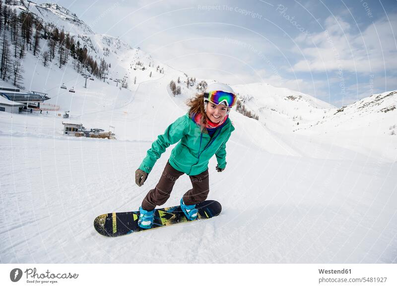 Österreich, Altenmarkt-Zauchensee, lächelnde junge Frau beim Snowboardfahren Snowboards weiblich Frauen Snowboarden Wintersport Wintersportart Wintersportarten
