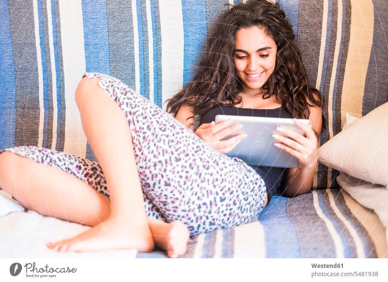 Teenager-Mädchen sitzt auf der Couch und betrachtet Tablette Tablet Computer Tablet-PC Tablet PC iPad Tablet-Computer Teenagerin junges Mädchen Teenagerinnen