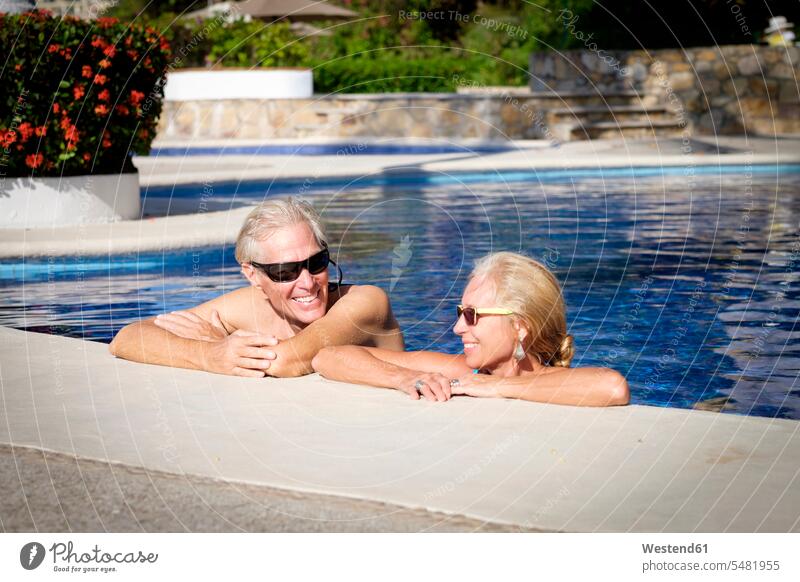 Glückliches Seniorenpaar im Schwimmbad Urlaubsort Ferienort Resort Urlaubsresort Erholungsort genießen geniessen Genuss Gemeinsam Zusammen Miteinander
