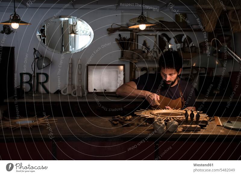 Handwerker, der in seiner Werkstatt einen Spiegel herstellt Korbflechterei Kunsthandwerk Kunsthandwerker Korbmacher Korber Gewerbe Handwerksberuf
