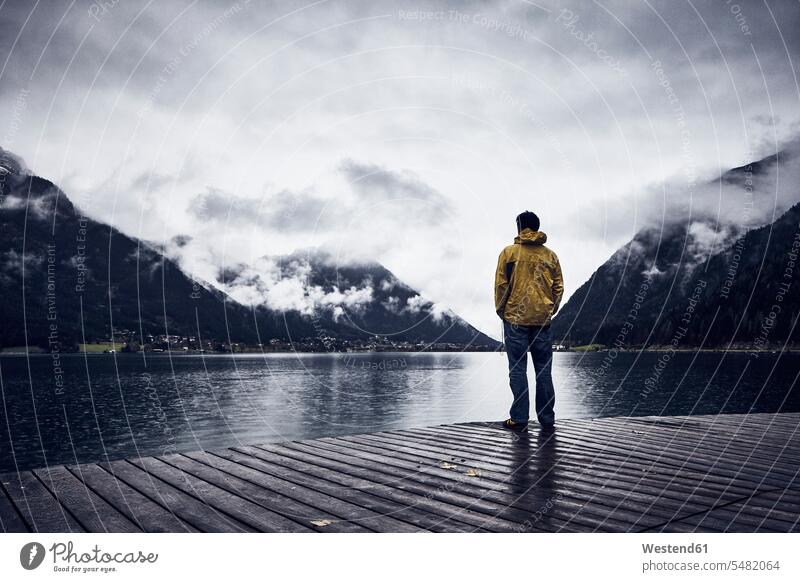 Österreich, Tirol, Achensee, Mann an der Strandpromenade stehend Männer männlich trübes Wetter truebes Wetter Holzsteg Holzstege Steg Stege Freizeit Muße steht