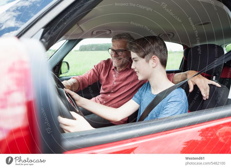 Vater lehrt Sohn Autofahren autofahren lächeln lehren unterrichten beibringen üben ausüben Übung trainieren Söhne Wagen PKWs Automobil Autos Papas Väter Vati