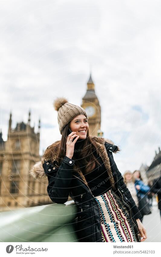 UK, London, glückliche junge Frau telefoniert mit einem Smartphone vor dem Palace of Westminster Palast Paläste Palaeste Schloss Städtereise City Trip Kurztripp