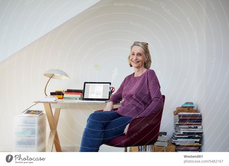 Porträt einer lächelnden reifen Frau zu Hause mit Laptop am Schreibtisch Notebook Laptops Notebooks Portrait Porträts Portraits weiblich Frauen Computer Rechner