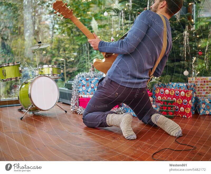 Mann spielt E-Gitarre vor dem Weihnachtsbaum Elektrogitarren E-Gitarren ausgelassen Ausgelassenheit Textfreiraum Vorstellungskraft Phantasie Erfindungsgabe