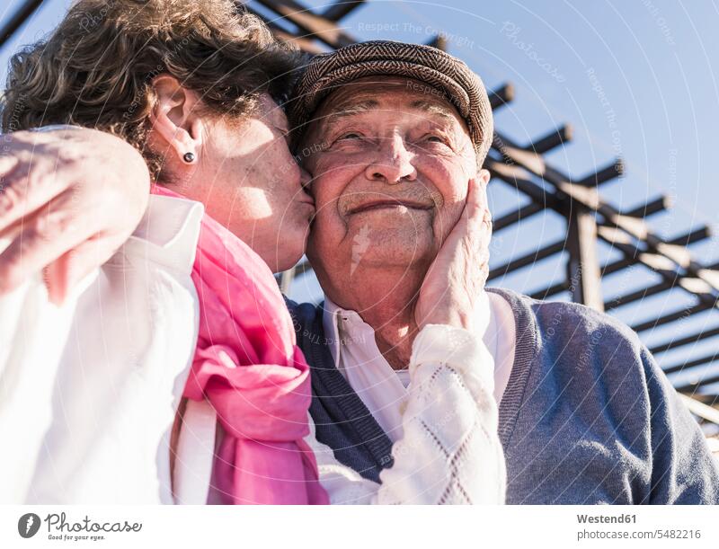 Porträt eines glücklichen älteren Mannes, der von seiner Frau geküsst wird Küsschen Kuesschen Portrait Porträts Portraits Seniorenpaar älteres Paar