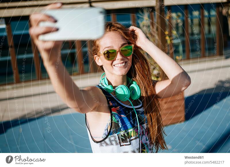 Lächelnde junge Frau mit verspiegelter Sonnenbrille macht Selfie mit Smartphone Selfies weiblich Frauen Erwachsener erwachsen Mensch Menschen Leute People
